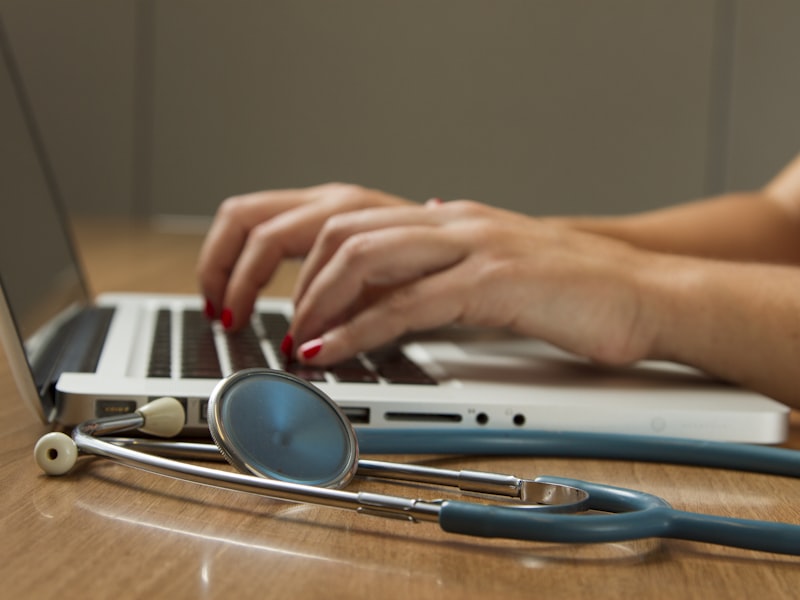 Medical professional using laptop with stethoscope — representing AI-powered hospital management system.